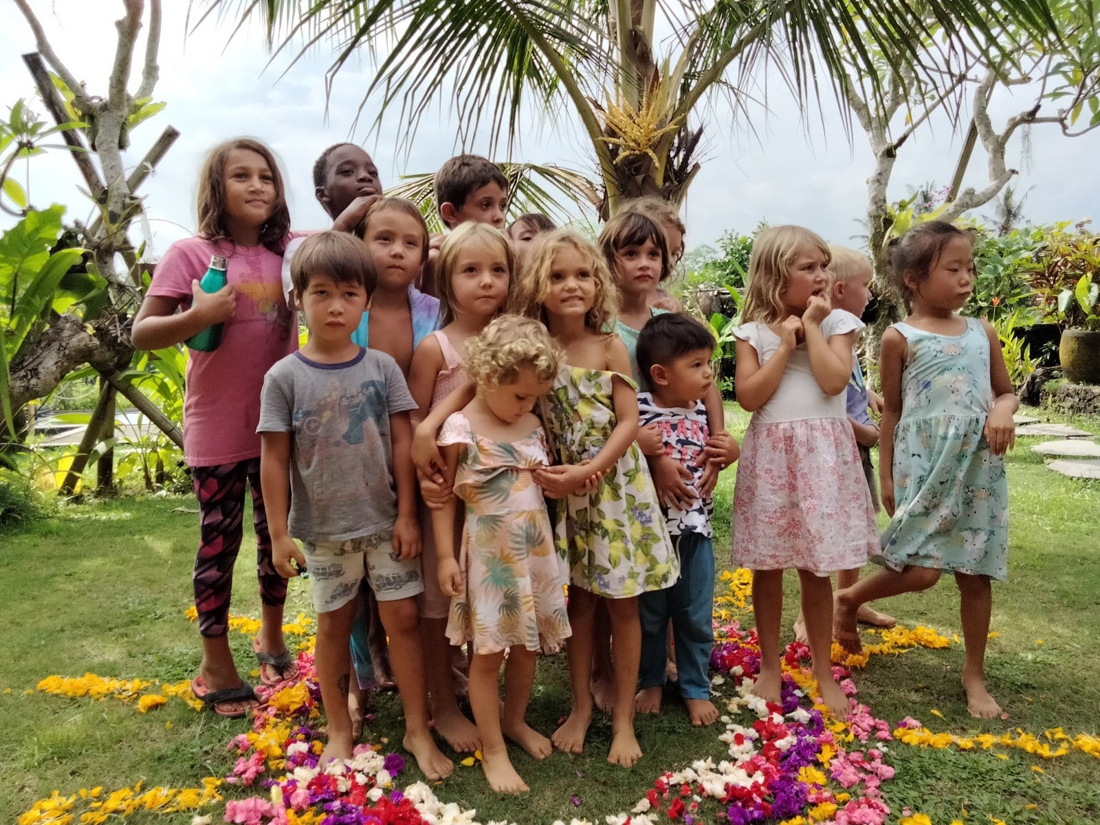 Children stand together in a circle of flowers at Empathy School.